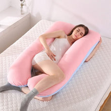 Pink maternity U pillow used in bed for side sleeping and gentle bump cushioning through pregnancy.