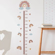 Height chart with rainbow and cloud design on a wall next to a wooden table.