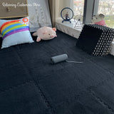 Children's room with dark play mat, colorful pillow, and toys near a window.