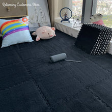Children's room with dark play mat, colorful pillow, and toys near a window.