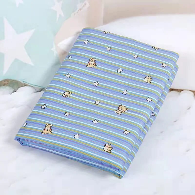 Folded blue striped fabric with teddy bear and star patterns on a white surface.