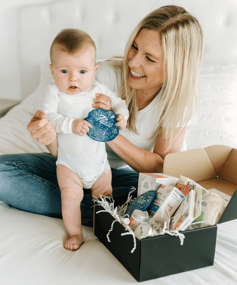 A woman holding a baby next to a box of baby products.