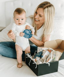 A woman holding a baby next to a box of baby products.