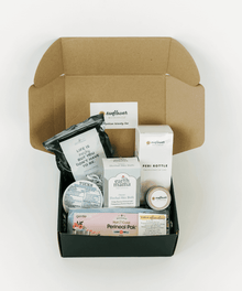 Opened postpartum healing box showing the self-care items included for recovery, comfort, and daily routines.