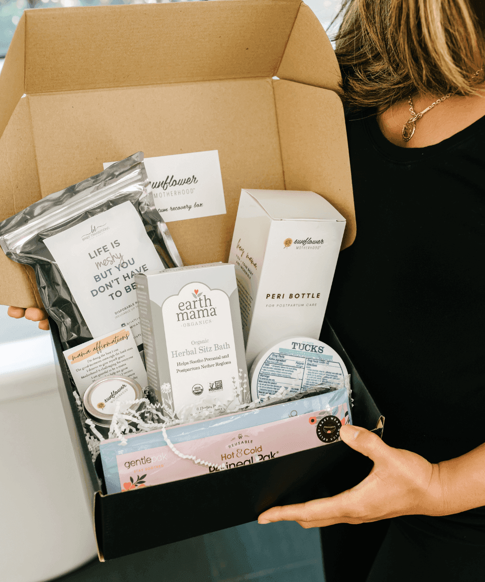 Person holding a box of baby products with Earth Mama and Tuck's branding.
