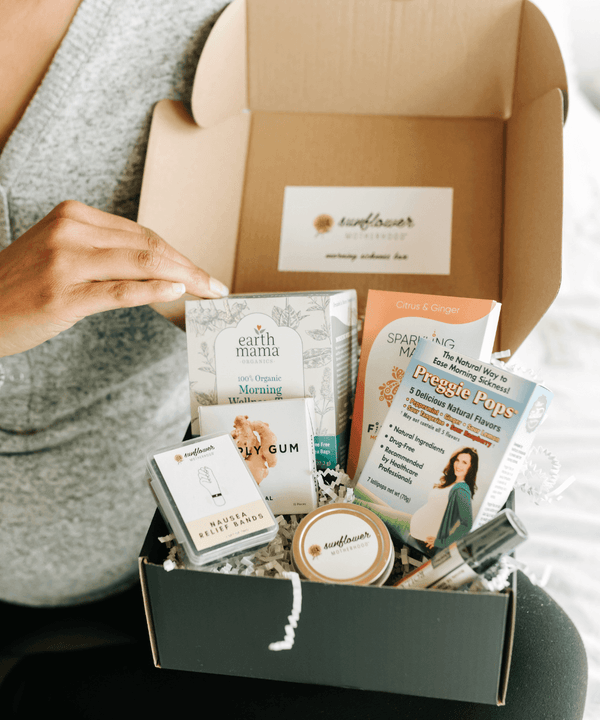 Unboxing a morning sickness relief box for pregnancy with care products and a guidebook for expecting moms.