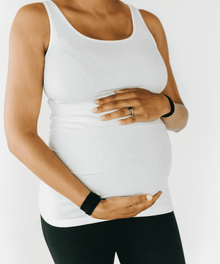 Nausea relief wristbands worn by a pregnant woman in everyday maternity clothing for all-day morning sickness relief.