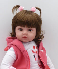 Premium soft silicone reborn toddler doll with brown hair and pink vest for lifelike newborn-style doll play.