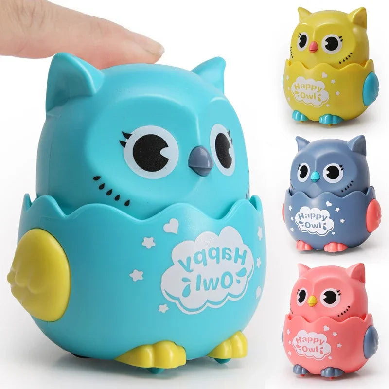 Finger pressing a blue owl toy with yellow, grey and pink owls beside it