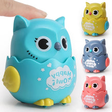 Finger pressing a blue owl toy with yellow, grey and pink owls beside it