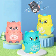 Pink, yellow and teal owl toys on round stands against a blue backdrop with a flying grey owl