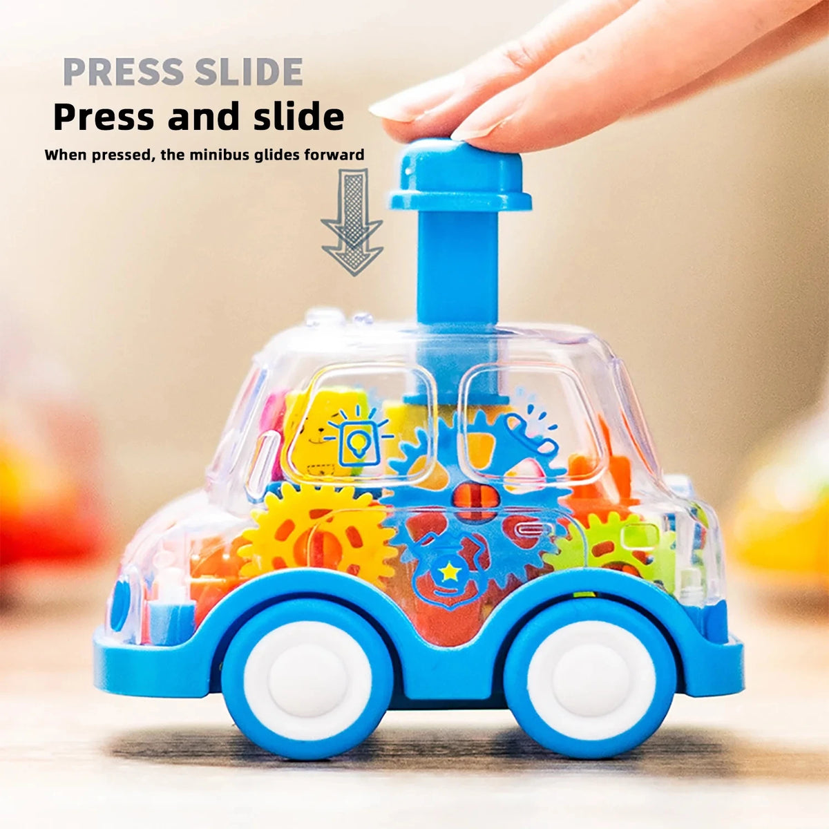 Hand pressing the button on top of a transparent blue gear toy car to make it glide forward