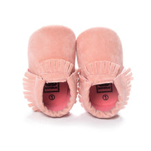 PU suede leather newborn baby moccasin shoes shown next to a baby's foot for size reference.