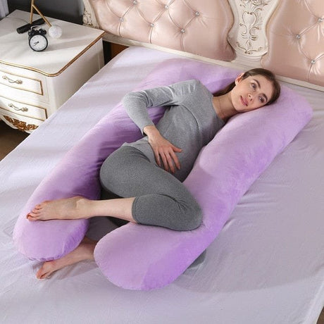 Woman lying on a purple U-shaped body pillow in a bedroom setting.