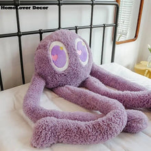 Purple heart-eyed plush ball pillow placed on a bed for bedroom decor and cuddling.