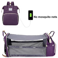 Portable folding baby crib mommy bag in purple, shown with phone charging for travel days.
