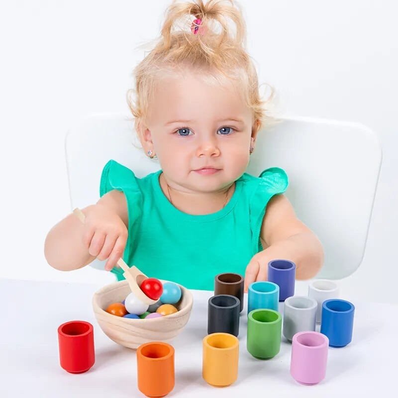 Rainbow Ball and Cups wooden Montessori toy played by a child for hand-eye coordination and independent quiet play.