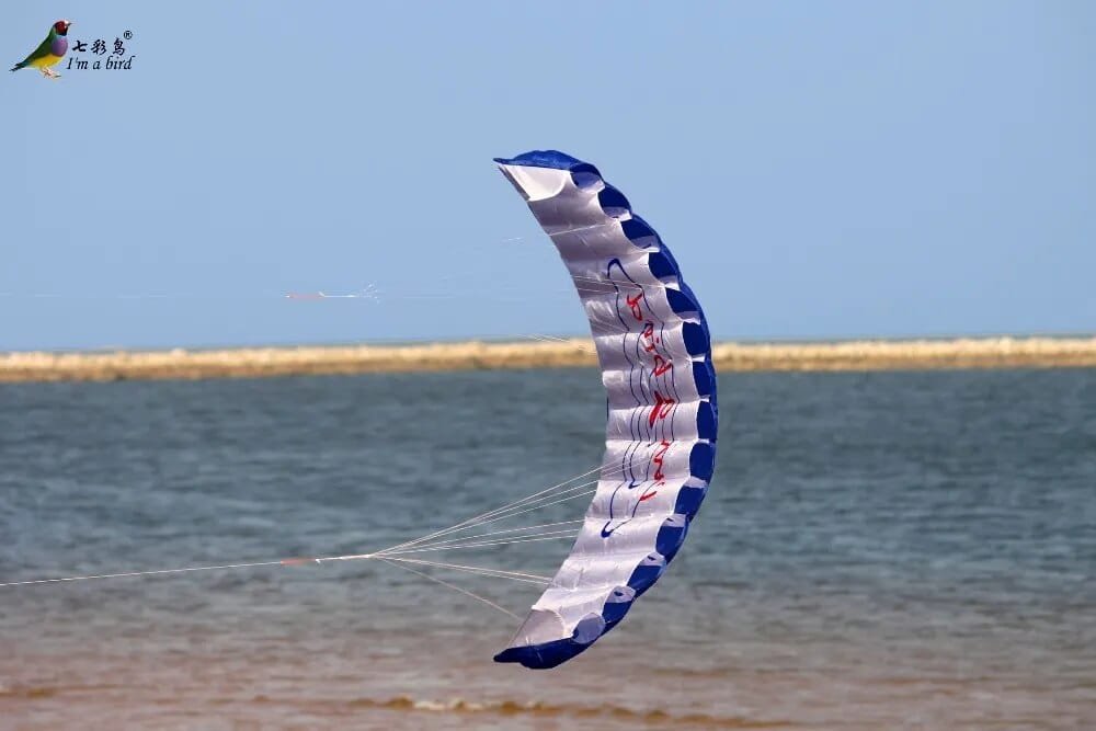 Dual line rainbow beach kite flying over coastal water for outdoor fun, holidays and family days out.