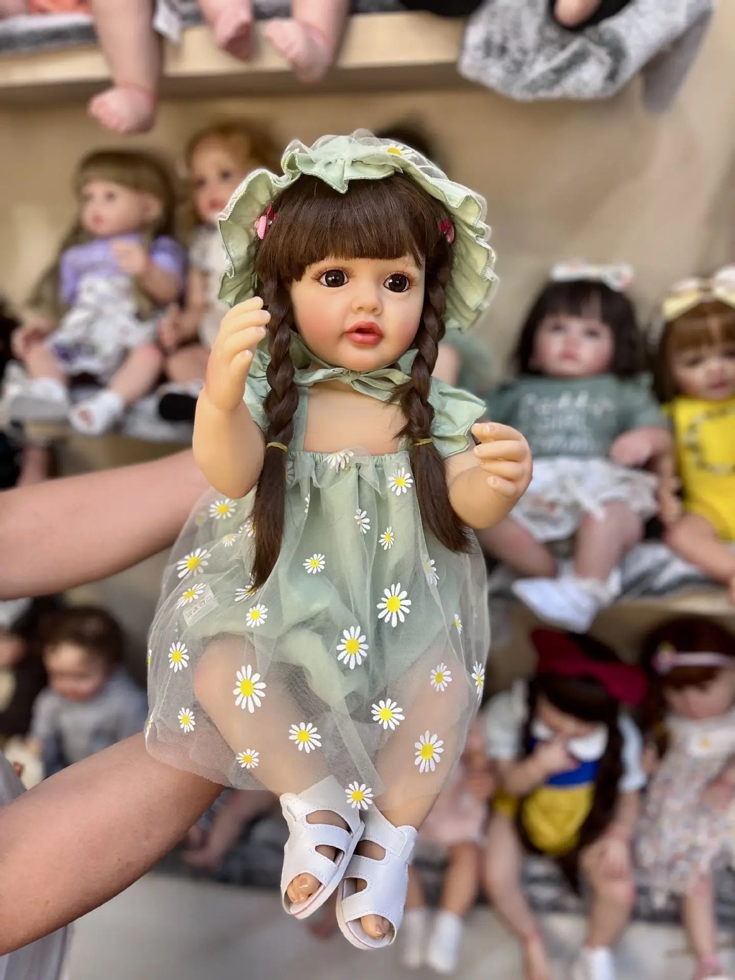 Realistic full silicone Reborn Doll Betty Princess in a green floral dress held in hand to show full body size for collectors.