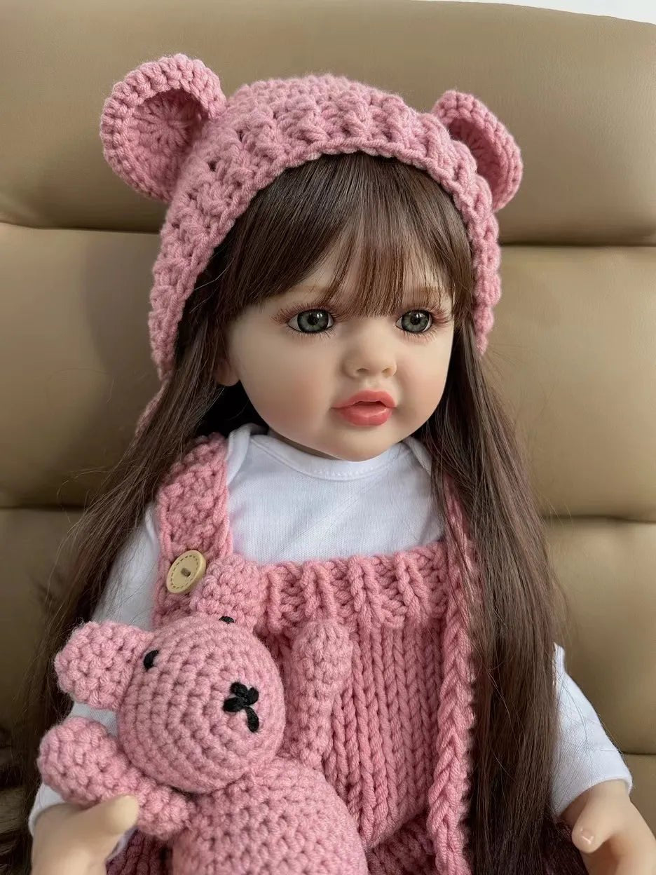 Realistic Reborn Baby Doll in a pink knitted bear-ear outfit with matching teddy, a silicone newborn girl doll for cuddling and gifting.