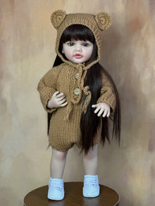 Realistic Reborn Baby Girl Doll with long hair in soft silicone wearing a knitted bear set for cosy cuddles and gifting.