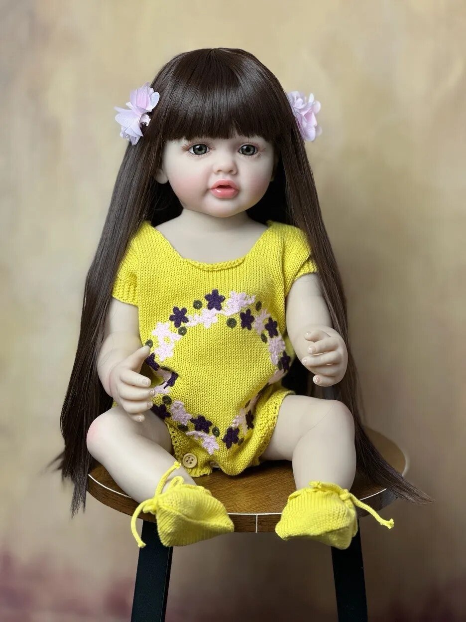 Reborn Baby Doll with long dark hair in a yellow floral outfit, a realistic silicone girl doll for toddler play and collecting.