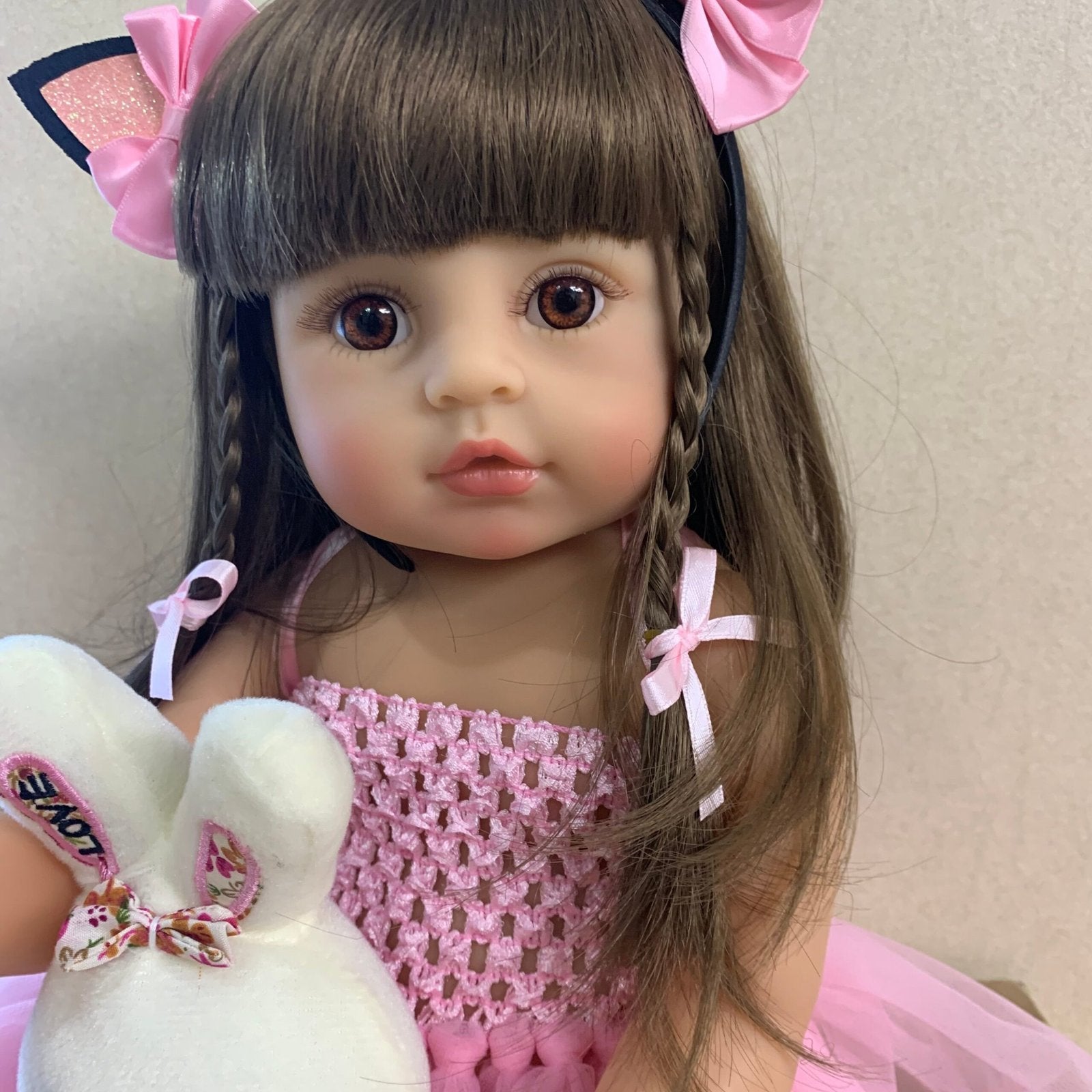 Reborn bath toy doll in pink princess styling with braided hair and white plush for bathing routines, play, and gifting.