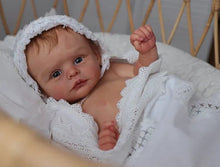 Reborn newborn doll wrapped in white lace with bonnet for keepsake display and collector styling.