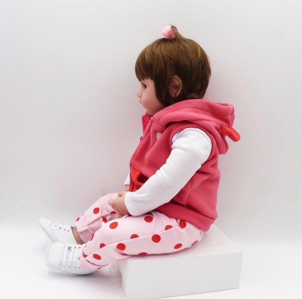 Child wearing a pink outfit with a hood and polka dot pants.