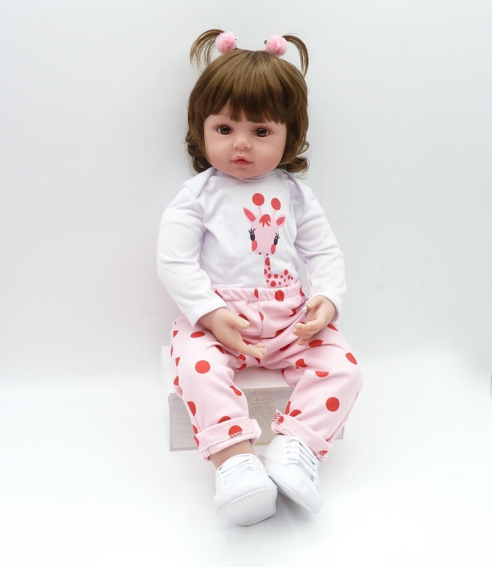 Doll wearing a white shirt with a pink giraffe design and pink pants with red polka dots on a white background.