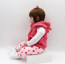 Reborn toddler doll in a pink hooded top and polka dot trousers, a soft silicone doll for dressing and cuddling.