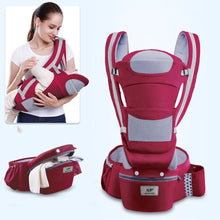 Red and grey ergonomic baby carrier worn with an infant for supported front carrying and daily errands.