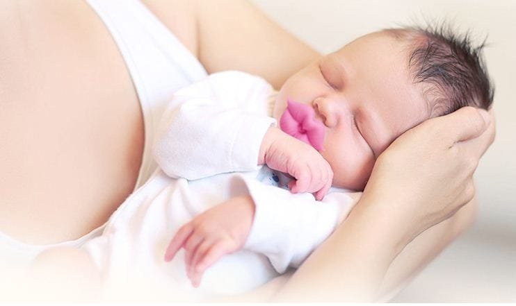 Red Kiss Lips Baby Pacifier soothing a sleeping newborn for calmer naps and gentle self-settling at bedtime.