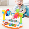 Smiling baby on a rug with a rotating musical piano keyboard toy with colorful spinning parts