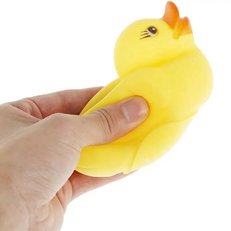 Rubber duck bath toy held in hand to show its easy-grip size, sized for small hands during bath time and paddling pool play.