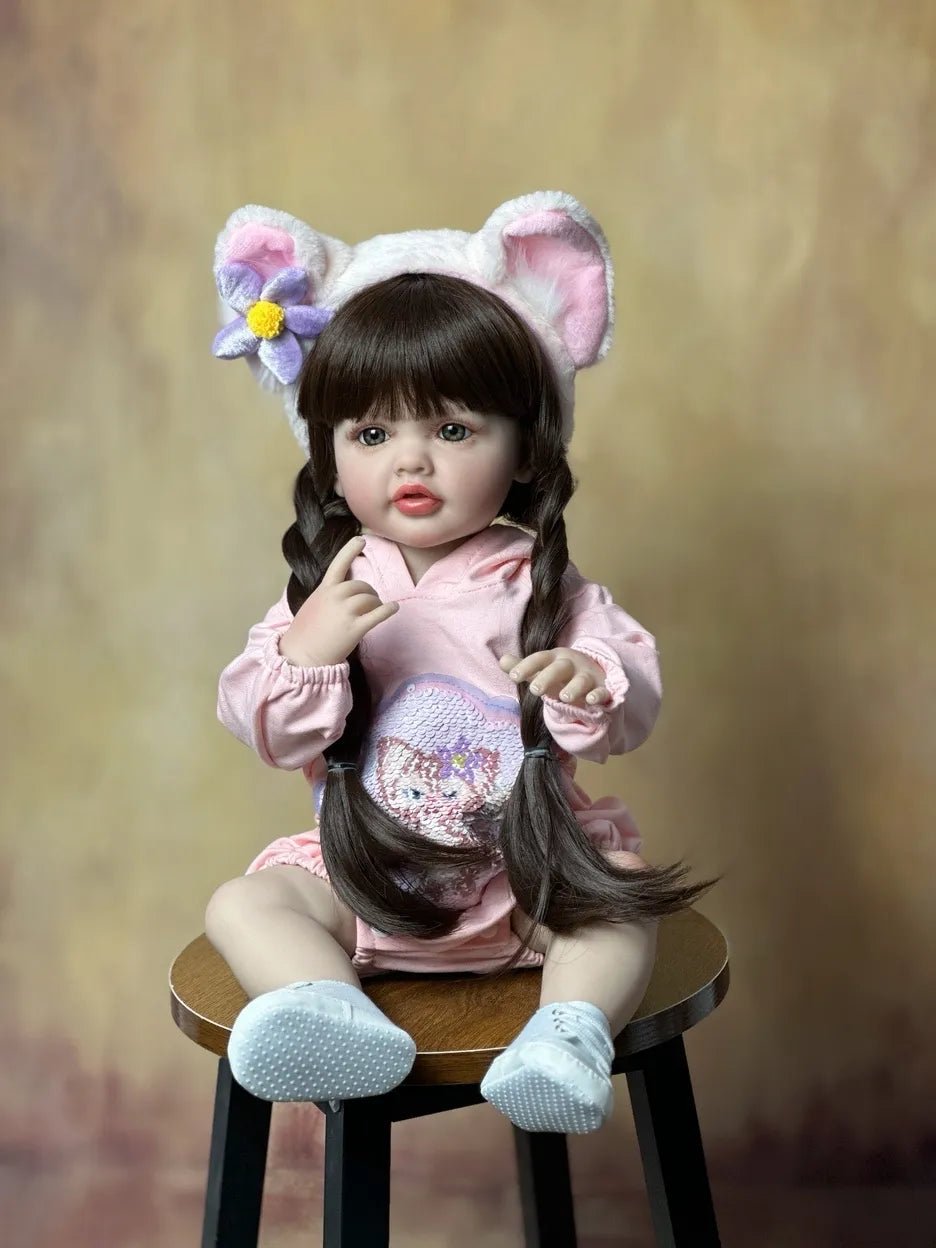 Silicone Reborn Baby Girl Doll with long hair in a bunny-ear pink outfit for playful dress-up and cosy cuddling.