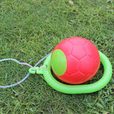 Red ball with a green handle on grass