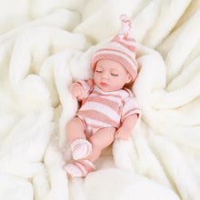 Newborn baby doll in pink and white striped outfit on a soft white blanket