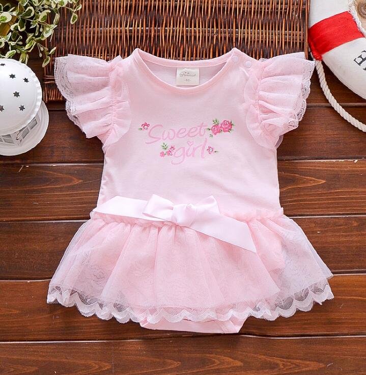 Pink baby dress with ruffled sleeves and a bow on a wooden surface (option 2)