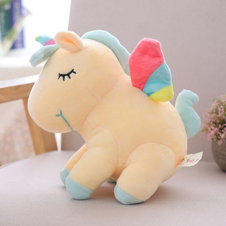 Plush unicorn toy with colorful wings on a light surface