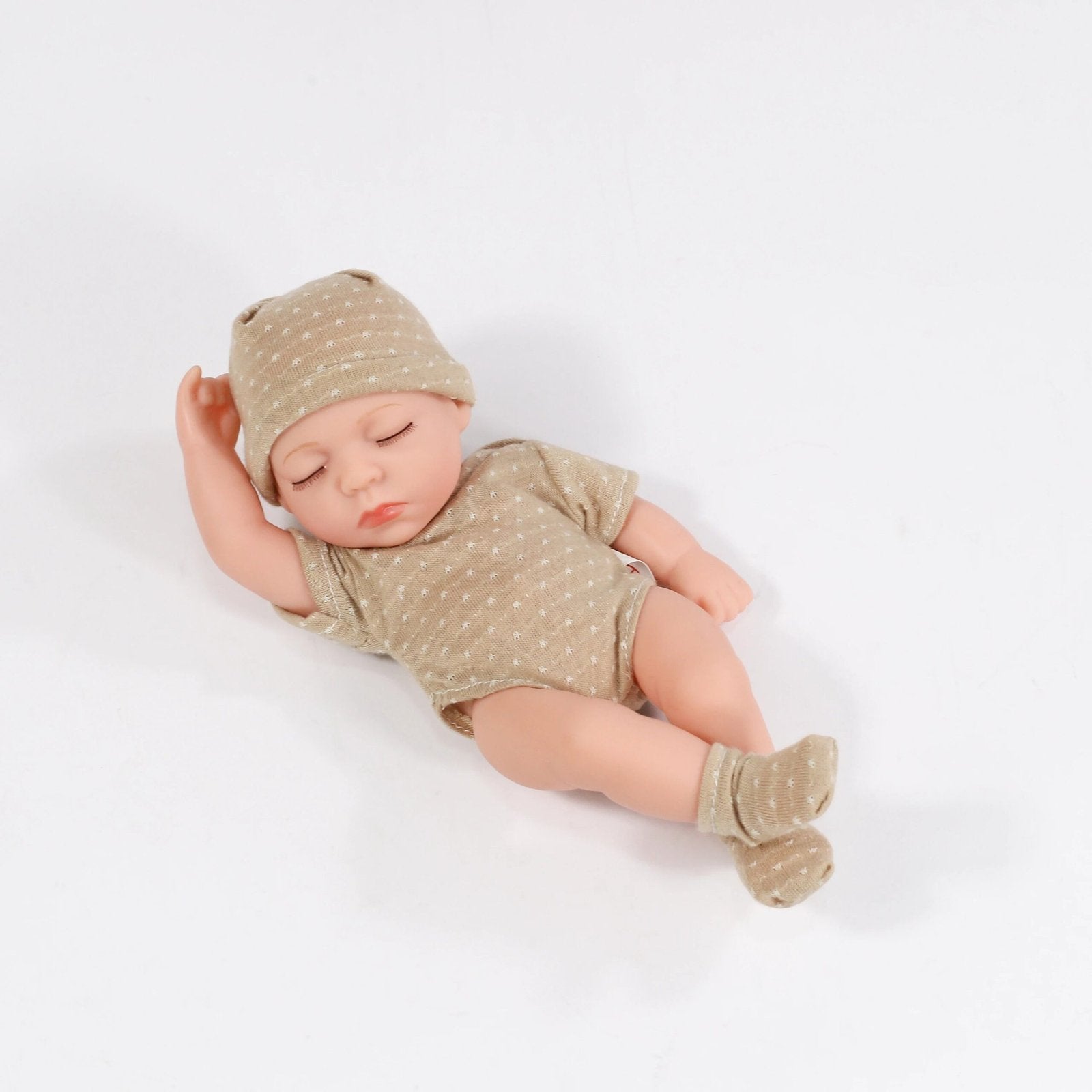Newborn baby in a beige outfit and hat.