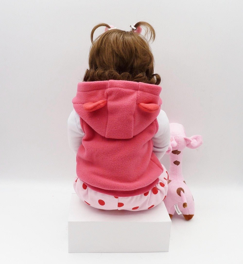 Child wearing a pink hooded outfit with animal ears and a matching pink toy 