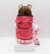 Child wearing a pink hooded outfit with animal ears and a matching pink toy 