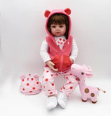 Child's doll in pink outfit with matching hat and shoes, surrounded by a pink stuffed giraffe on a white background.