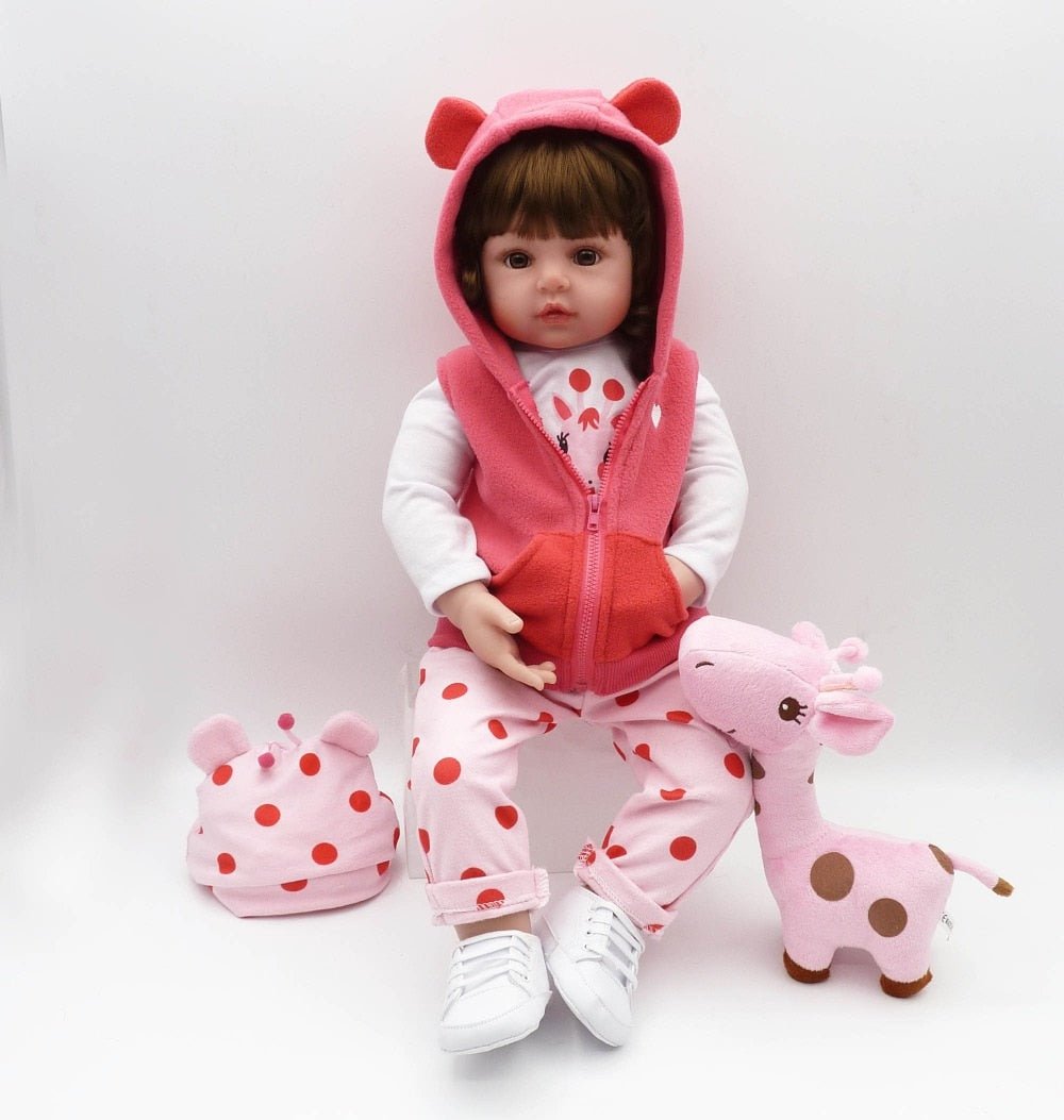 Child's doll in pink outfit with matching hat and shoes, surrounded by a pink stuffed giraffe on a white background.