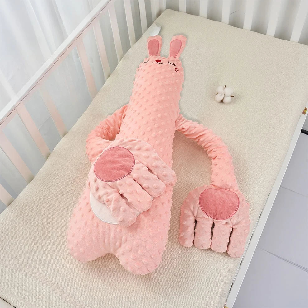 Pink rabbit plush pillow with long arms and rose palms laid on a crib mattress