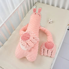 Pink rabbit plush pillow with long arms and rose palms laid on a crib mattress