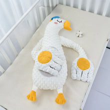 White goose plush pillow with spread orange feet on a crib mattress, second view