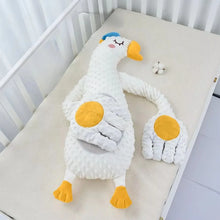 White goose plush pillow with long arms and orange palms laid on a crib mattress
