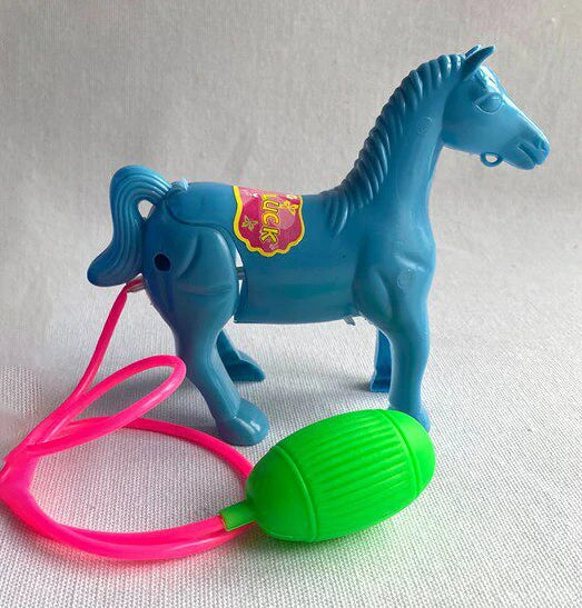 Blue plastic horse toy with a pink tube and a green bulb on a grey surface